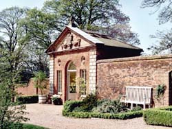 sunny corner of the garden with seat in front of a warm brick wall